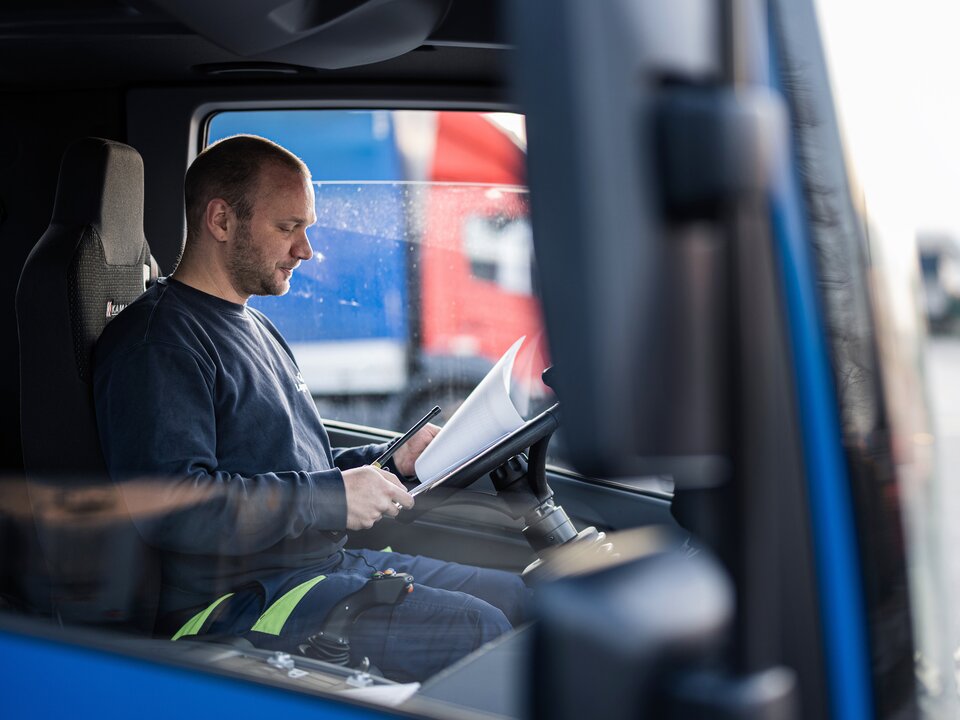 Lagermax LKW-Transport Fahrerkabine Ein Arbeiter sitzt in einer LKW Fahrerkabine und sieht sich Dokument an